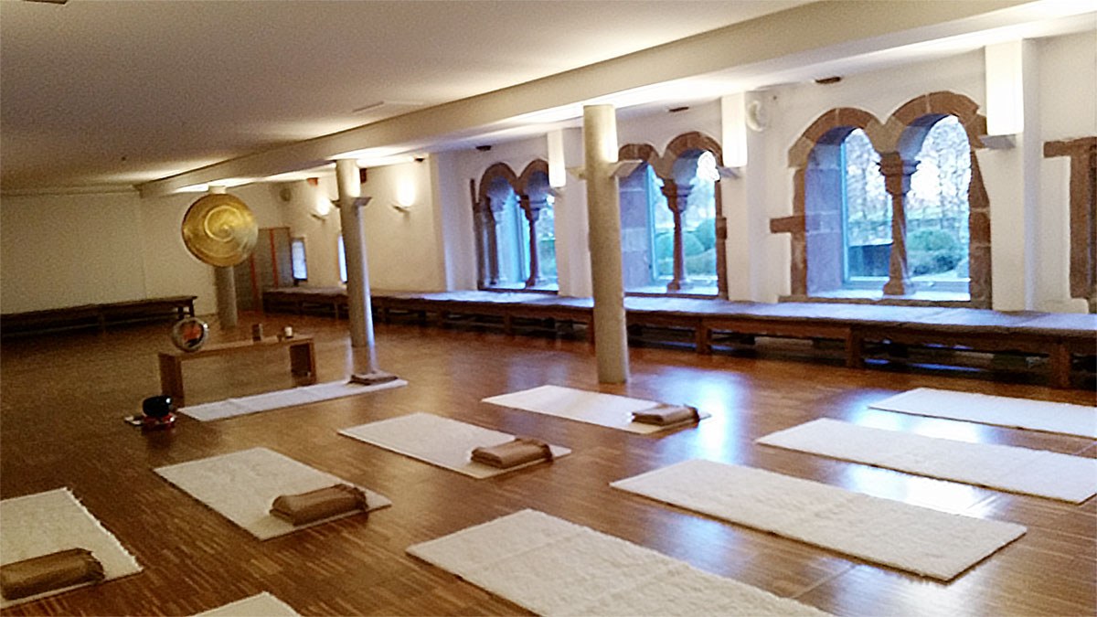 Zendo mit Gong und Sitzkissen im Licht der Bogenfenster