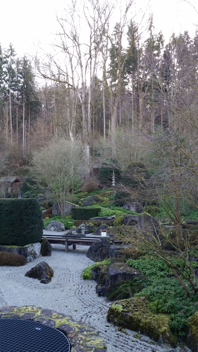 Zen-Garten mit geharktem Kies vor Waldhang